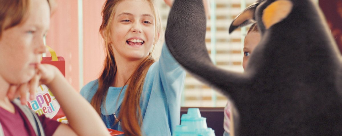 A smiling girl giving our McDonald's VFX penguin "high-five".