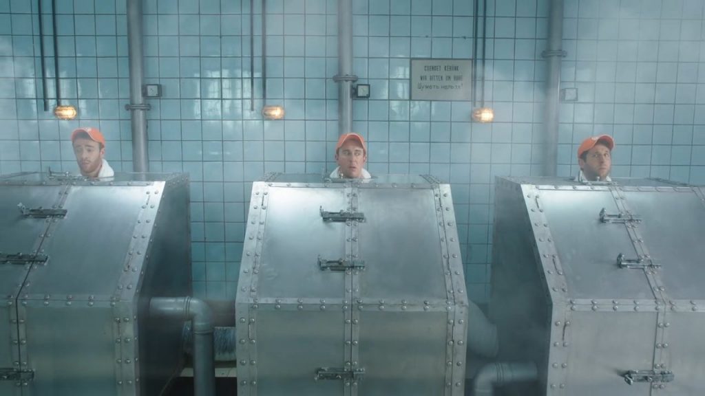 Three men wearing orange Zweifel "Cractiv" baseball caps steaming in russian metal-saunas.